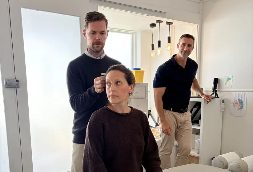 Two chiropractors talking a patient through their care in the treatment room